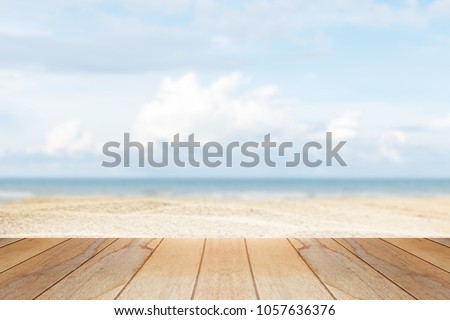 wooden table in front of abstract blurred background of summer beach Royalty-Free Stock Photo #1057636376
