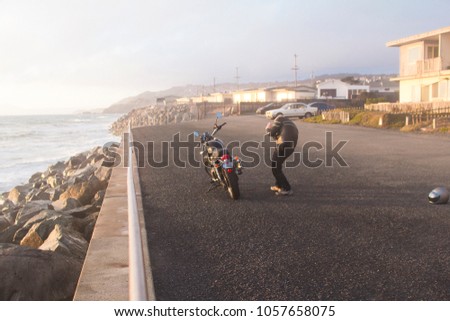 Man taking picture of his motorcycle at Pacifica Beach California