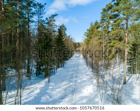 Aerial drone view of a winter road landscape. Snow covered forest and road from the top. Sunrise in  nature from a birds eye view. Aerial photography. Aerial photo. Quadcopter. Winter road