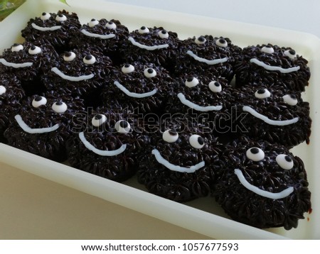 A rows of chocolate cup cakes with smile face and eyes in close up shot