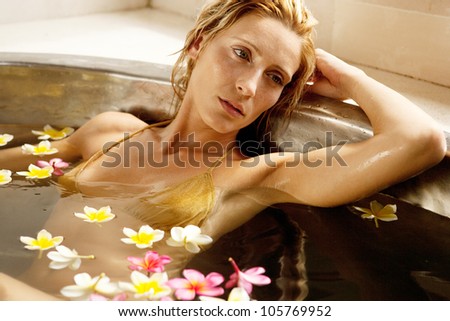 Close up of an attractive woman in a bath of flowers, relaxing.