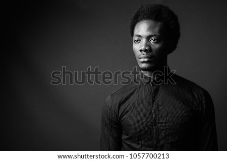 Studio shot of young handsome African businessman against gray background in black and white