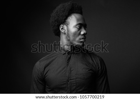 Studio shot of young handsome African businessman against gray background in black and white