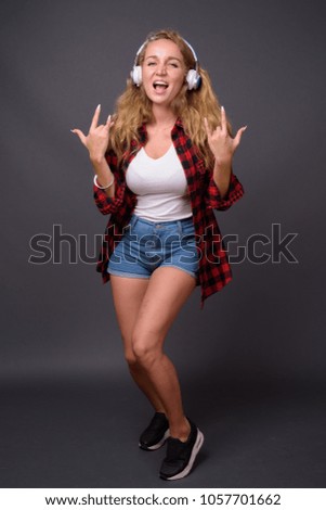 Studio shot of young beautiful woman with long wavy blond hair against gray background