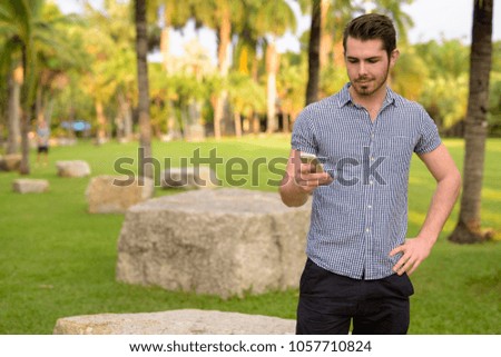 Portrait of young handsome man relaxing at the park in Bangkok, Thailand