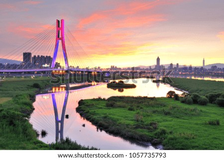 Taipei City's New North Bridge reflects the sunrise sky with colored clouds and ponds before dawn, beautiful views of the bridge and the sleeping city.