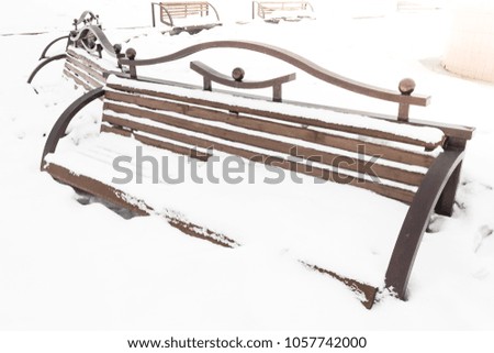 Wooden bench under the snow in the city Park