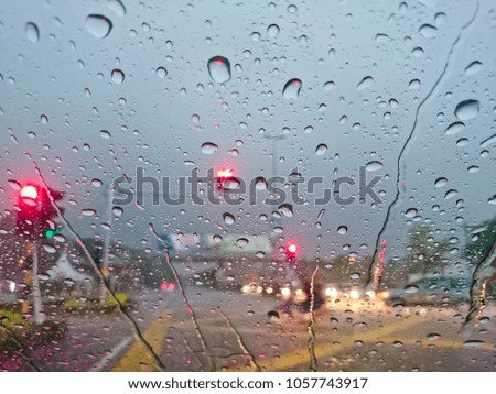 Rainy and water drop at front car glass. Blurred view while driving at the road
