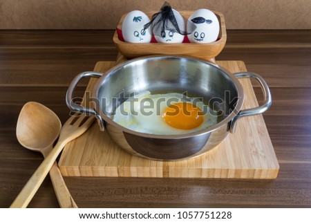 Three sad eggs in wooden box are looking at the omelet in Kitchen. Omelette funny egg concept.