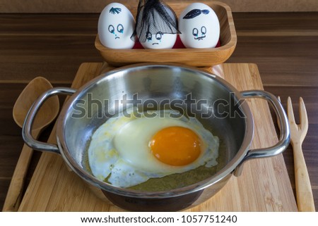 Three sad eggs in wooden box are looking at the omelet in Kitchen. Omelette funny egg concept.