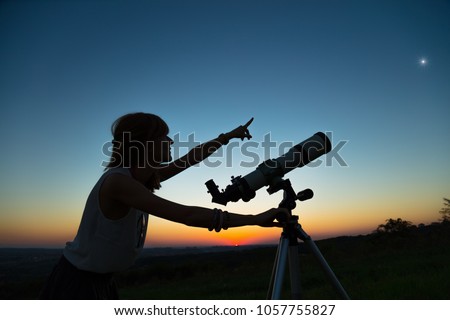 Young woman looking at the sky with a astronomical telescope. Royalty-Free Stock Photo #1057755827