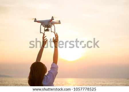 The UAV drone and photographer woman hands.drone copter flying with digital camera. UAV Drone with digital camera. Flying camera take a photo and video.The drone with camera takes pictures of the sky.