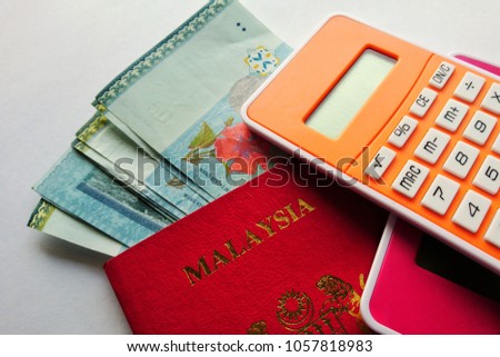 Close up shot of a Malaysia  passport with Ringgit Malaysia  currency and a calculator, with white background.