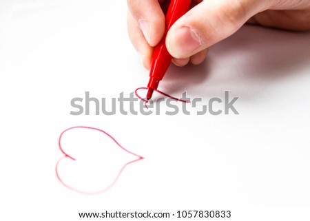 Child's hand draws a red felt-tip heart