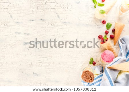 Summer sweet berries and desserts, various of ice cream flavor in cones pink (raspberry), vanilla and chocolate with mint on light concrete background copy space top view