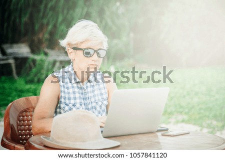 The girl is working behind a laptop on the beach. Office on the ocean, dream job. Freelance work concept. Toned image