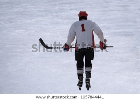 Alone hockey player going to slash puck at outdoor skating rink