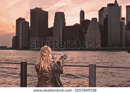 manhattan skyline and warm sunset with woman looking at binocular from brooklyn side