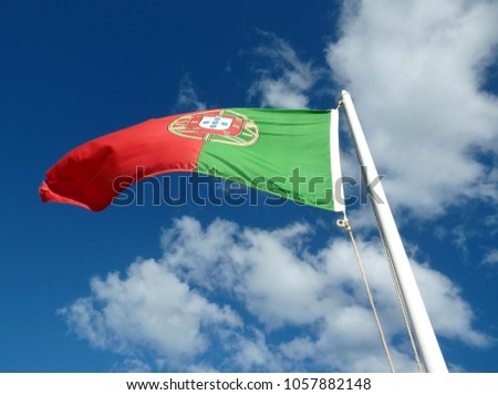 Waving portuguese flag on sunny blue sky, portugal.