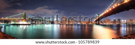 New York City Manhattan downtown skyline panorama with skyscraper and water reflection over East River at night
