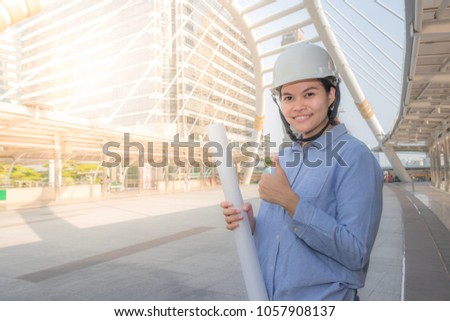 Asia woman engineer wears Safety Helmet holding technical drawing In the right of the picture looking on the life.
