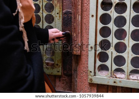  girl with a beautiful manicure opens an old unusual door to the yard