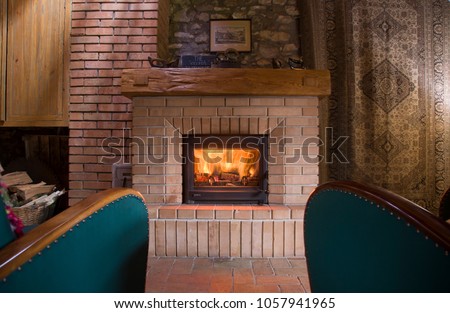 Moody fireplace indoor, with two green armchairs, and home-like ornaments around.