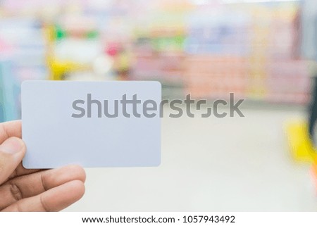 Blurred White card in hand on blurred Convenience Store background,
