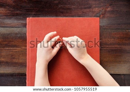 hands of kid playing with wedding rings on leather covered wedding album or book. Top view