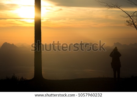 silhouette picture. The traveler looking sunrise in the high mountain 