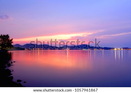 Colorful sky over lake and island with water reflection on sunset time background,Soft focus due to long exposure shot.