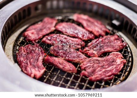 Cooking barbecue and grilled over charcoal on stove.  Raw beef slice for barbecue or Japanese style yakiniku food.