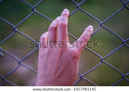 Hand in jail with girl and house of detention concept, vignette effect and selective focus. Royalty-Free Stock Photo #1057981145