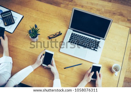 Generation Y office desk, young adults using smart phones at work