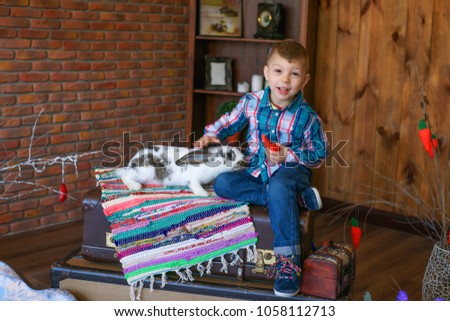 
Happy easter. Happy child, boy stroking an easter bunny in a photo studio on a wooden background