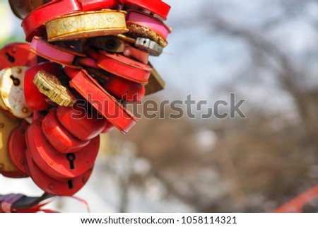 Red metal padlocks on a metal lattice, symbolizing eternal love. On hinged locks, the names of the newlyweds are written. Wedding tradition.