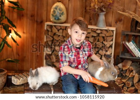 
Happy easter. Happy child, boy stroking an easter bunny in a photo studio on a wooden background