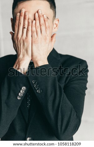 Man in black suit in the office on light background. Closed face