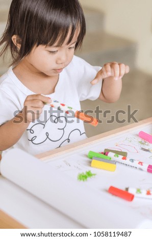 Little asian girl drawing picture with colorful marker pens at home