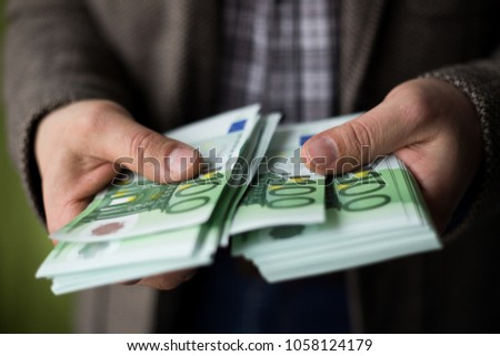 Man in a casual jacket counts and holds hundred 100 euro bills with his hands