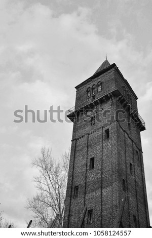 View of the old fire tower of red brick in the autumn evening. Vintage. Black and white image.