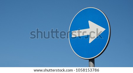 Regulatory signs, proceed in direction indicated by arrow traffic sign over blue sky