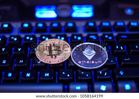 Bitcoin and Ethereum coins on a keyboard. Crypto currency coins on a computer black illuminated keyboard. Digital currency. Virtual money. Metal coins of Ethereum. Bussiness, commercial, exchange.