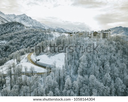 aerial mountain on a winter day with snowy trees and road between