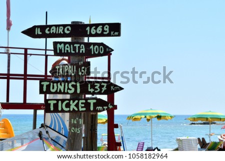 Multidirectional sign with mileage to distant cities and ticket office