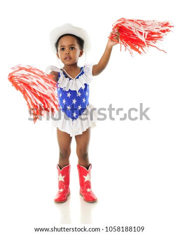An adorable African American 2 year old in a western red, white and blue outfit shaking her pom-poms for the USA.  On a white background.