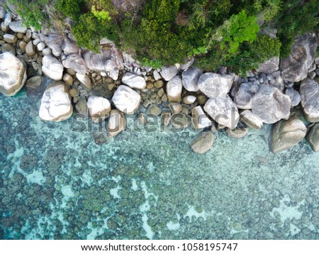 Aerial photo of rocky shoreline on the edge of clear blue water in Koh Lipe, Thailand