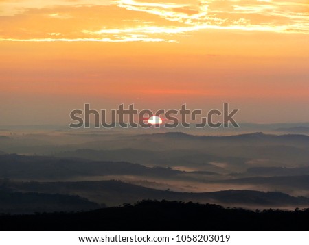 Golden and orange sunrise iluminating a forest. Montains, forests, hills are showed in lays in the picture