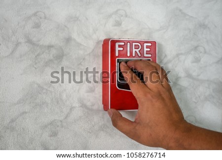 The hand of man is pulling fire alarm on the wall