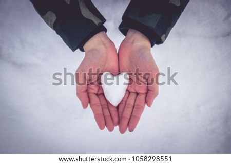 Close up of holding the snow heart shape in woman's hands, winter concept